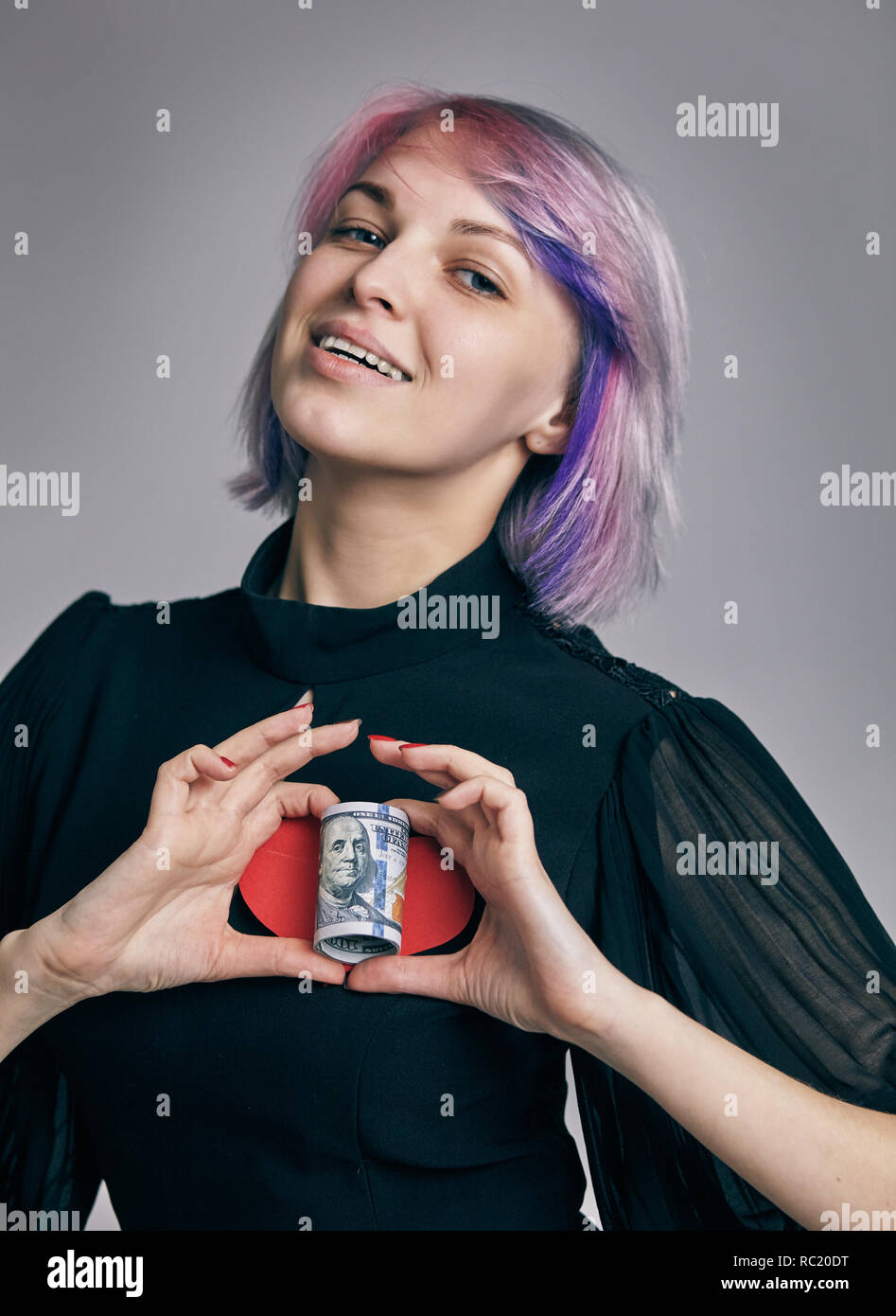 Un rouleau de dollars avec le coeur en deux mains de womans. amour money concept Banque D'Images
