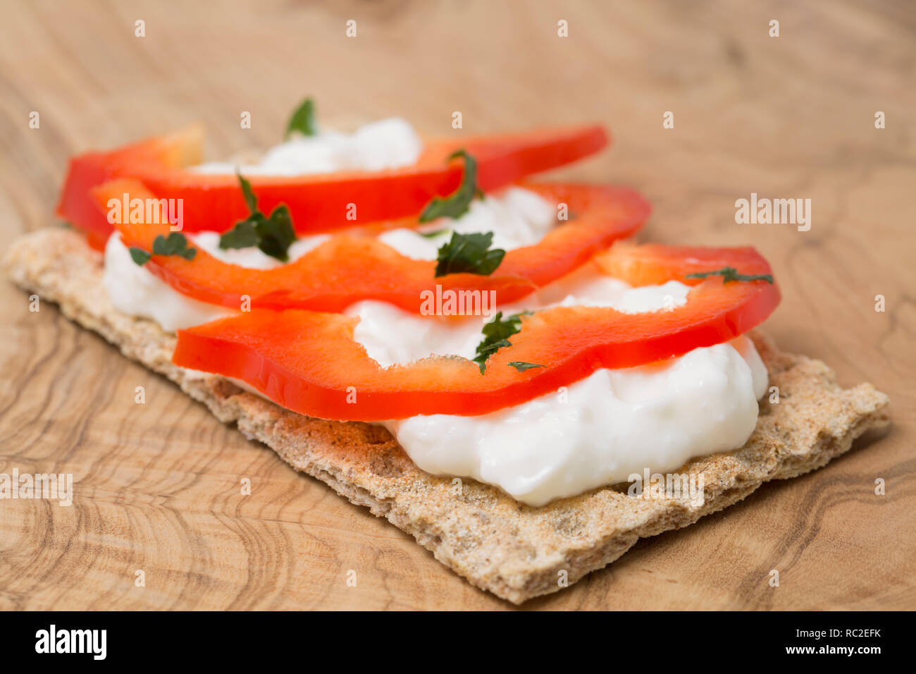 Un pain de seigle cracker propagation avec fat free cottage et les tranches de poivron rouge garni de persil. Sur une planche à découper en bois d'olivier. England UK GO Banque D'Images