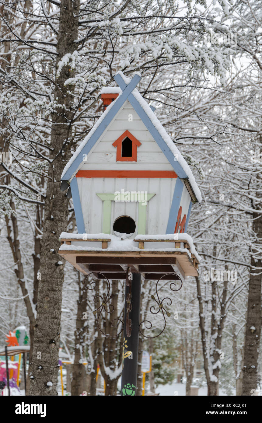 Wooden birdhouse accroché à l'extérieur en hiver, recouvert de neige Banque D'Images