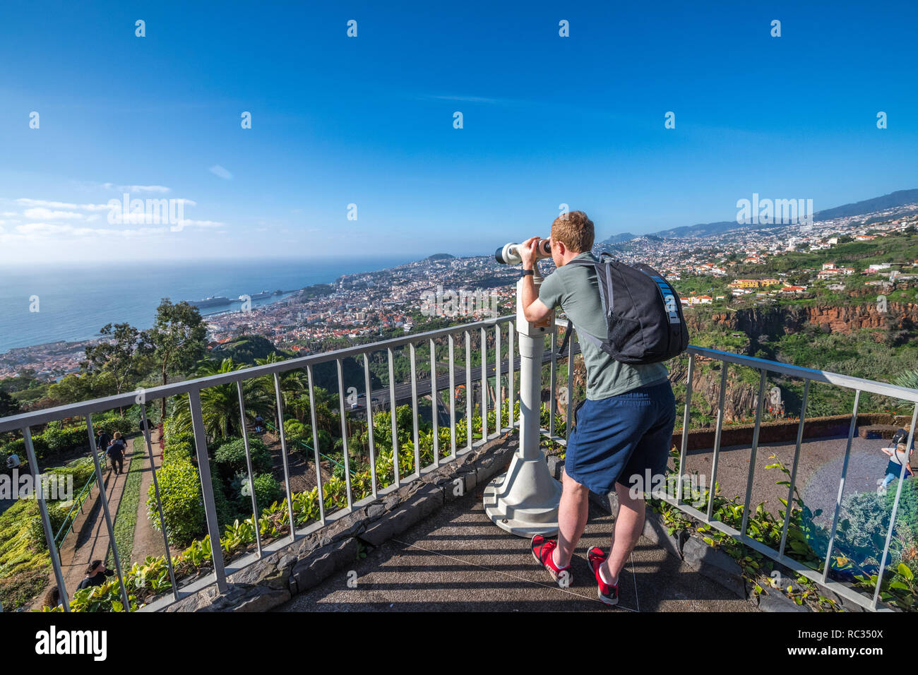 À l'aide d'un touriste mâle monté pilier paire de jumelles pour voir la ville de Funchal, Madère du jardin botanique. Banque D'Images