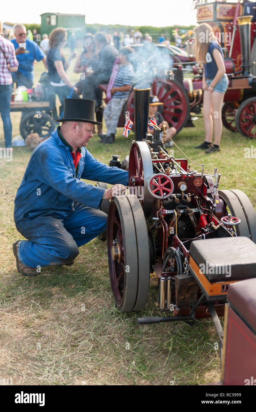 Homme à genoux en face d'un moteur de traction miniature à la vapeur Preston Rally, Kent, Angleterre Banque D'Images