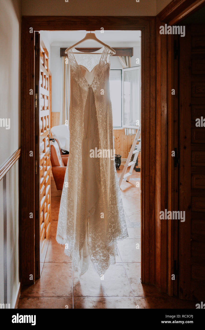 Une robe de mariée blanche accroché sur une porte en bois dans une maison rustique Banque D'Images