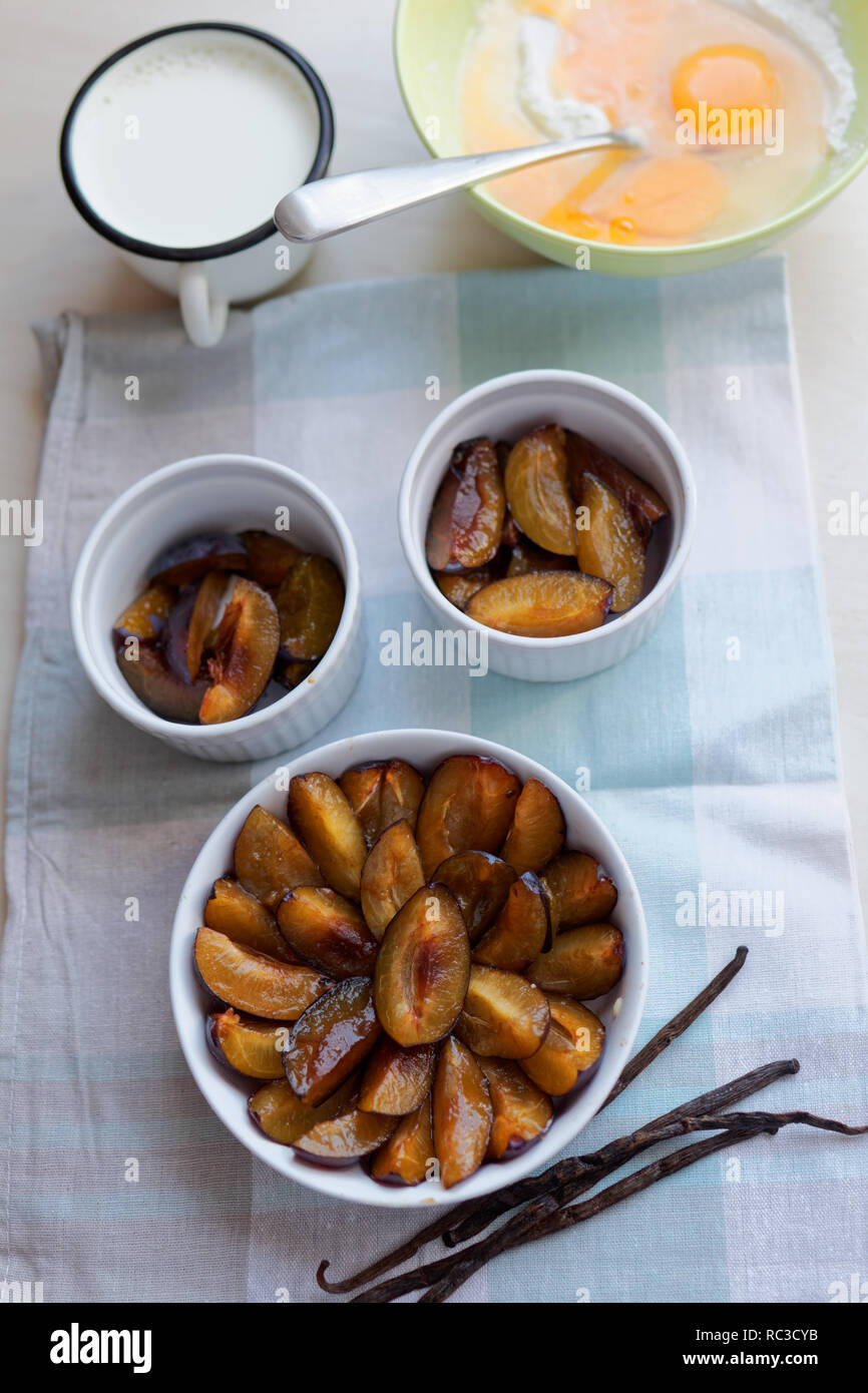 Ingrédients pour cuisiner clafoutis prune : prunes, farine, œufs, lait, vanille Banque D'Images