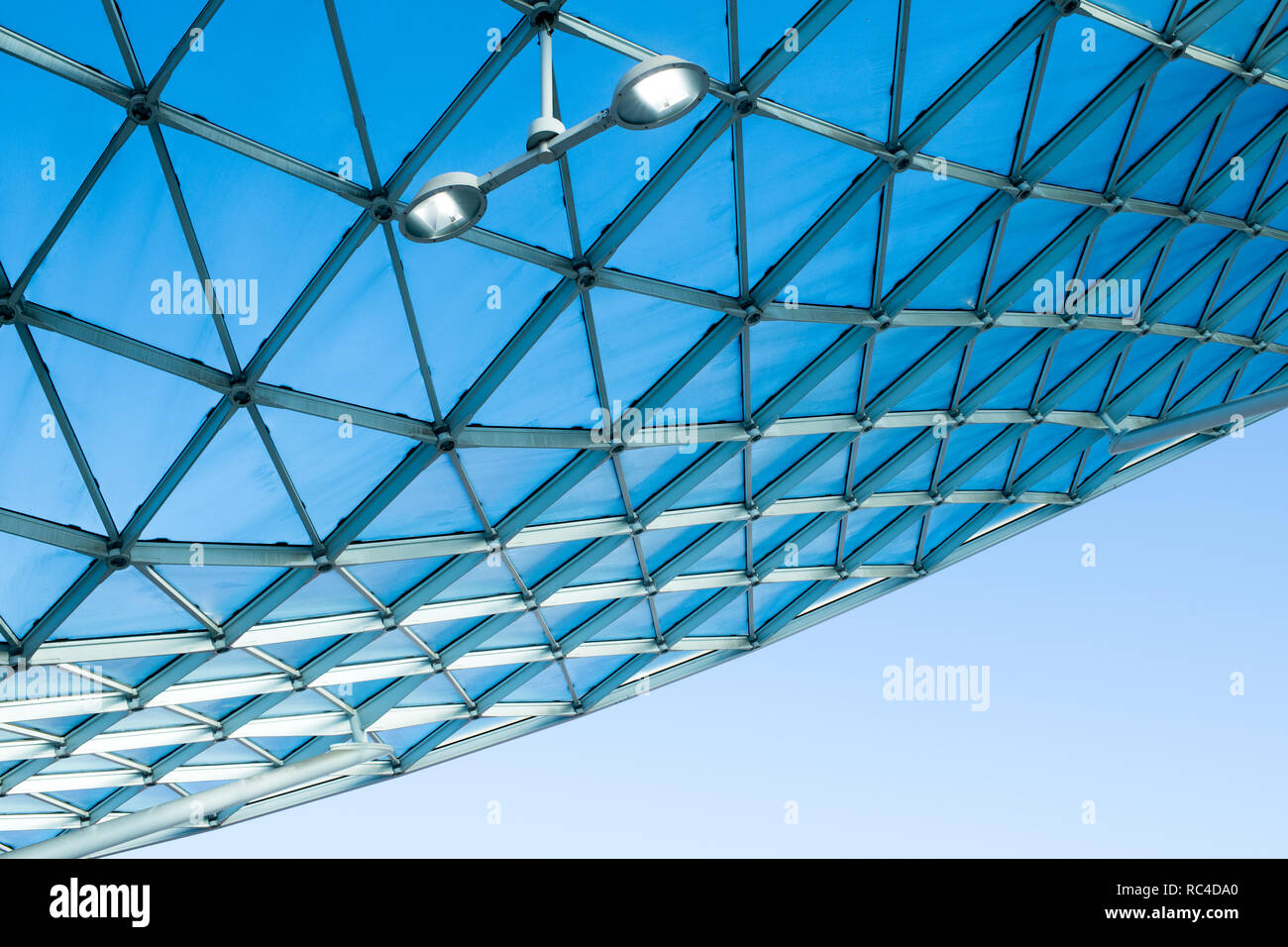 L'architecture moderne avec toit en verre design incurvé de structure d'acier. Low angle view avec ciel bleu, l'éclairage intérieur et mur blanc de l'immeuble Banque D'Images