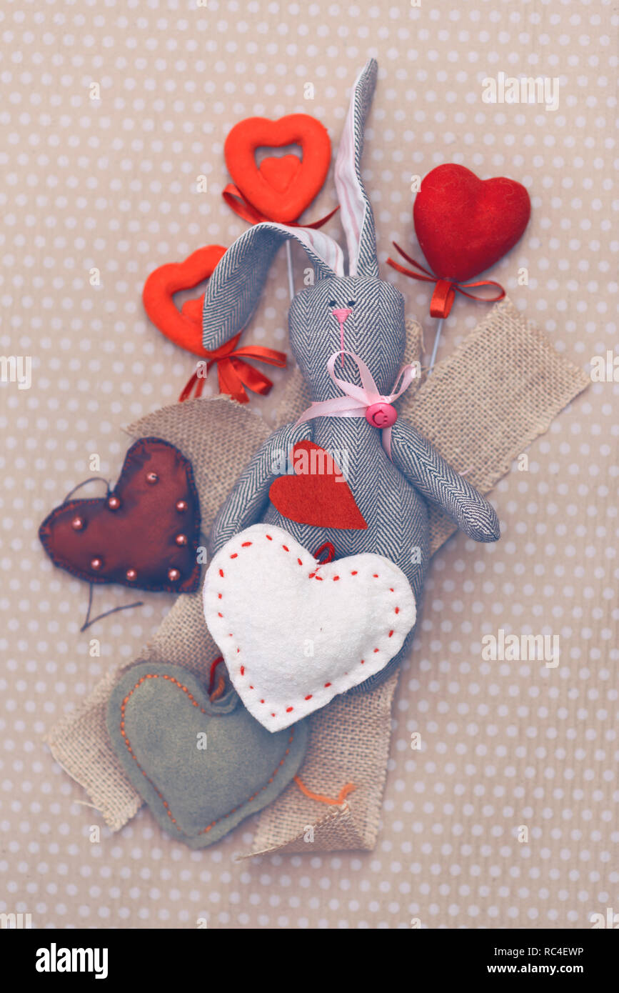 Valentines Day. Lapin tilde couché dans un tas de confectionner des coeurs. Valentine Day. Pendentif Coeur. L'espace pour le texte. Coeurs rouges. Dans les tons de l'image couleur à la mode Banque D'Images