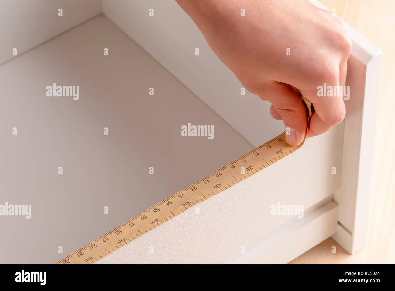 Un jeune homme tente de plier une table de chevet. Il mesure les étagères avec un outil de mesure. Banque D'Images