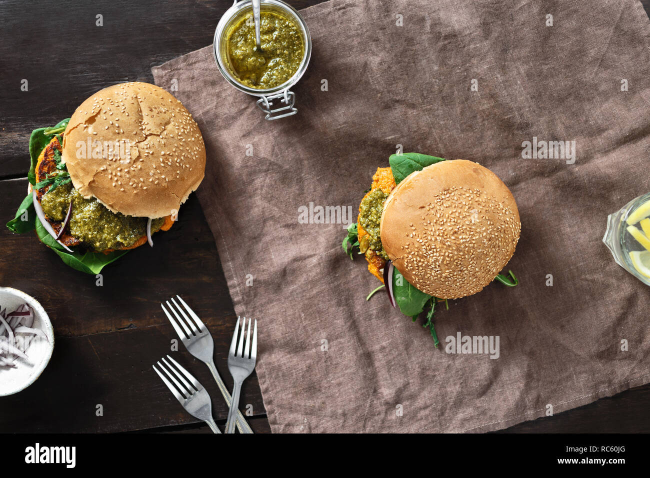 Concept alimentaire végétarien sain. Vue de dessus avec burger végétarien escalope de citrouille, Épinards, roquette et pesto végétarien servi sur la plaque sur le sol en bois Banque D'Images