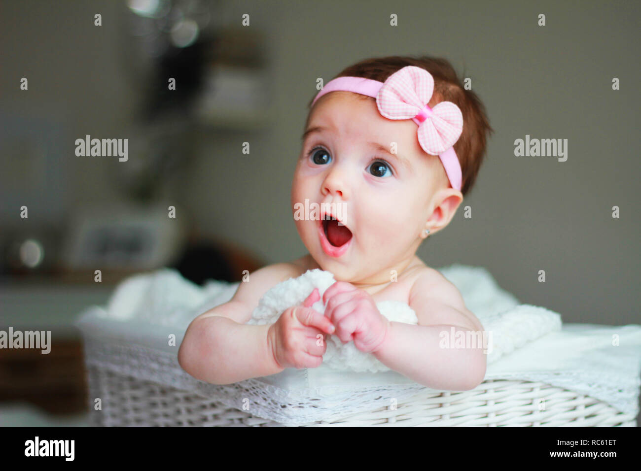 Cute baby girl, avec un archet sur ses cheveux, avec stupéfaction face Banque D'Images