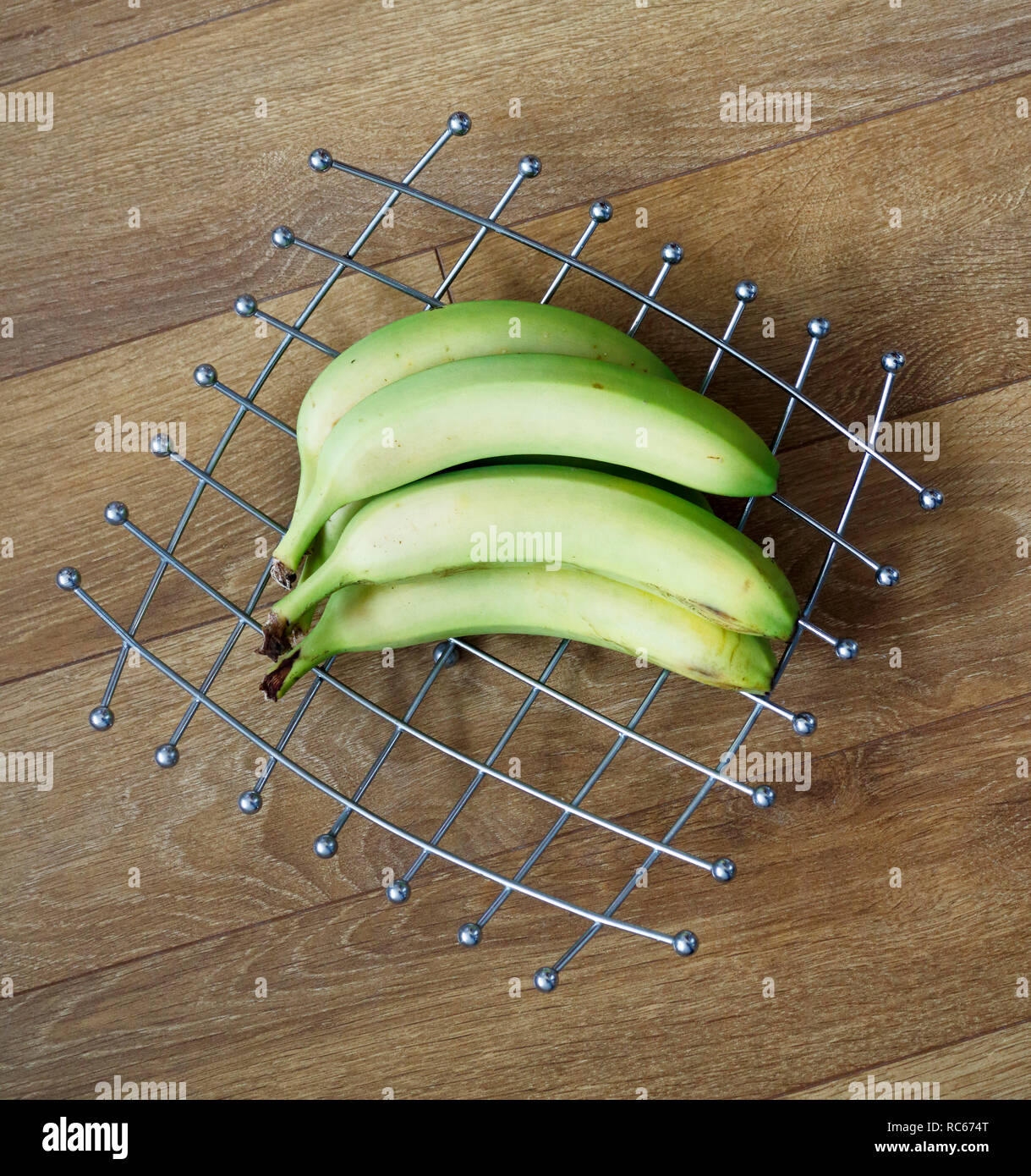 Quatre bananes maturation sur une grille d'acier inoxydable type design coupe à fruits. Banque D'Images