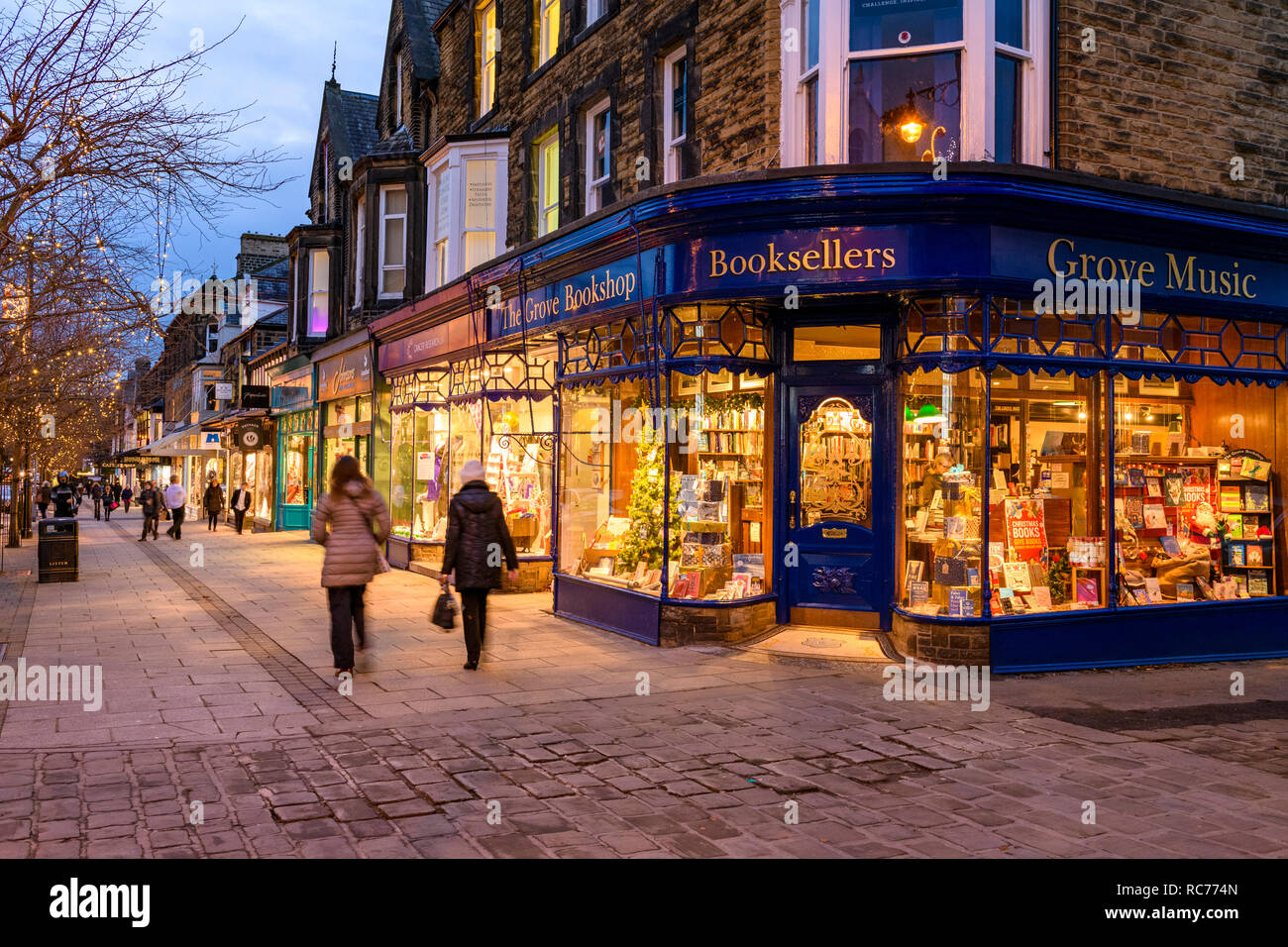 Golden glow lumières du soir et attrayants de fenêtre, l'affichage extérieur de la librairie Grove est accueillant (les gens passent devant) - Bradford, West Yorkshire, Royaume-Uni Banque D'Images