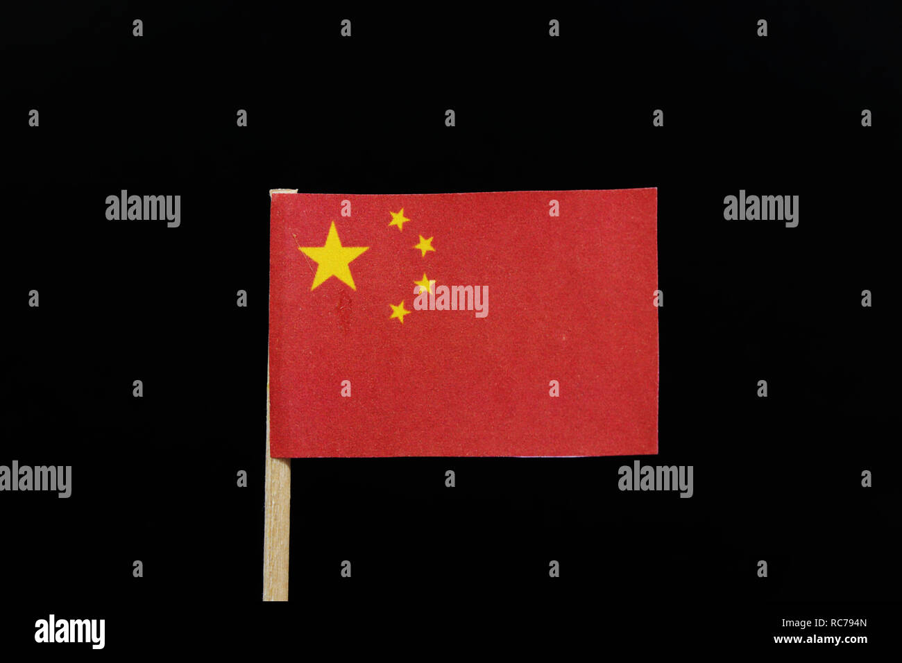 Un unique et simple pavillon de la Chine sur les cure-dents sur fond noir. Une grande étoile d'or dans un arc de quatre petites étoiles d'or, dans le canton, sur Banque D'Images