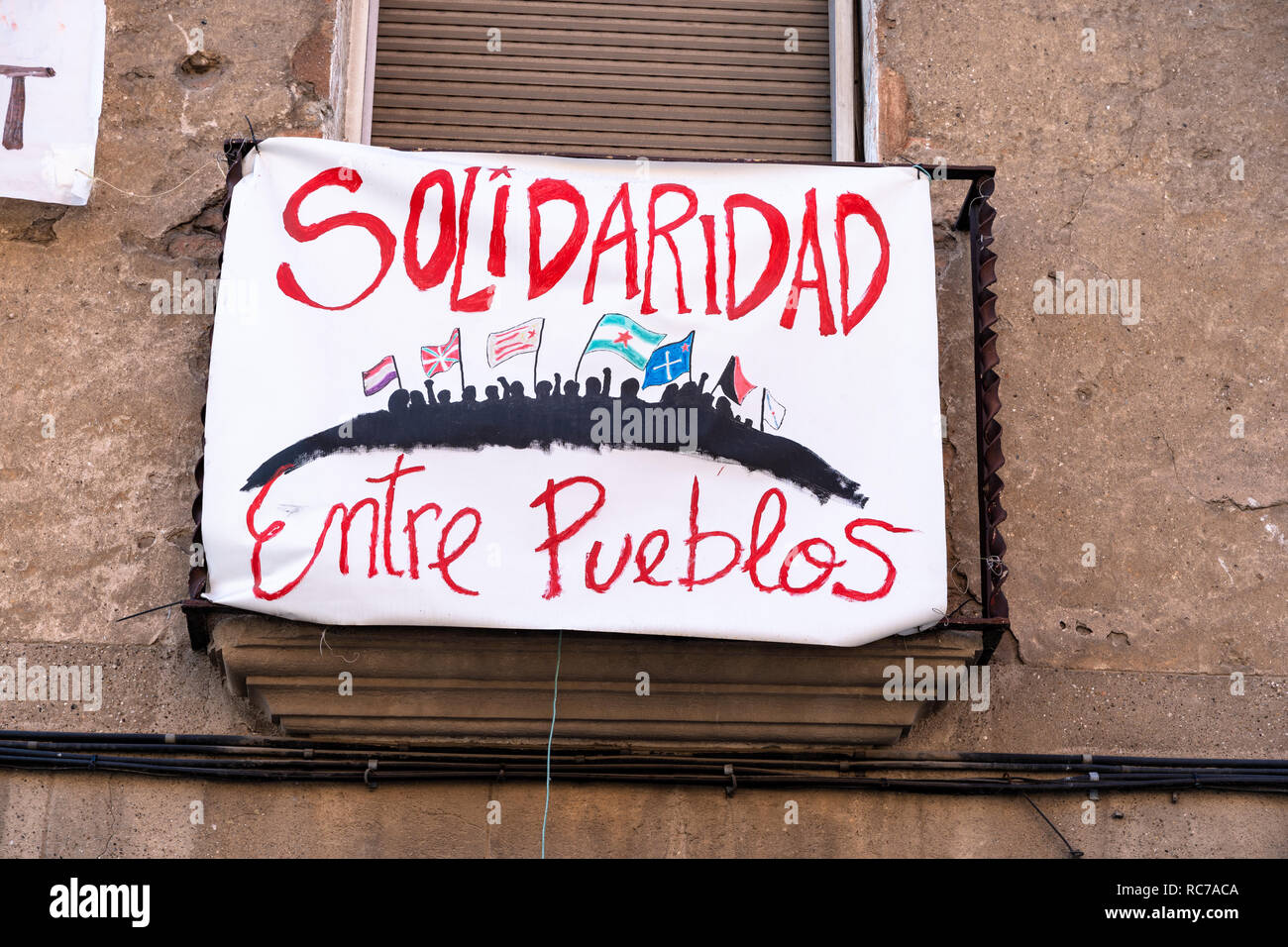 Avec le texte de l'affiche de "solidarité entre les peuples' accroché sur la façade d'une maison abandonnée à Barcelone, ​​Spain Banque D'Images