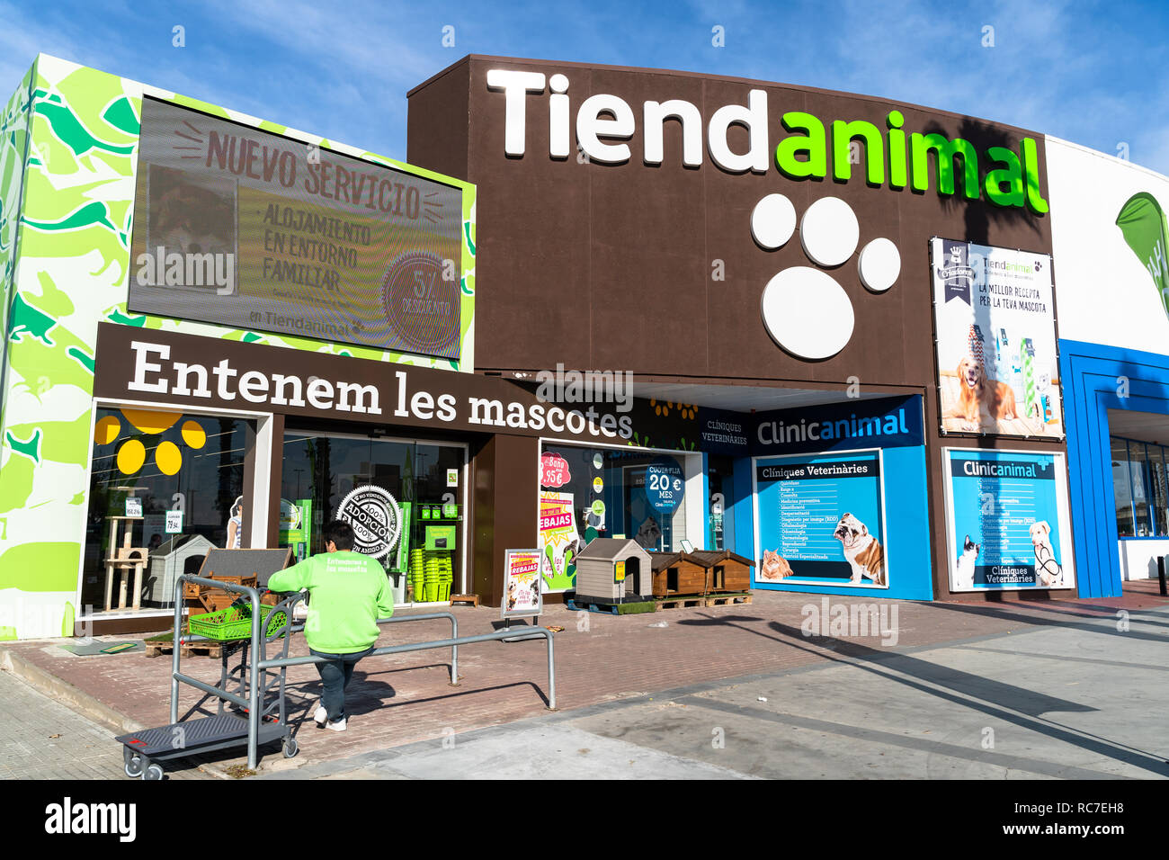 Façade d'Tiendanimal avec des affiches en langue catalane, avec un travailleur reposant à Sant Boi, Barcelone Banque D'Images