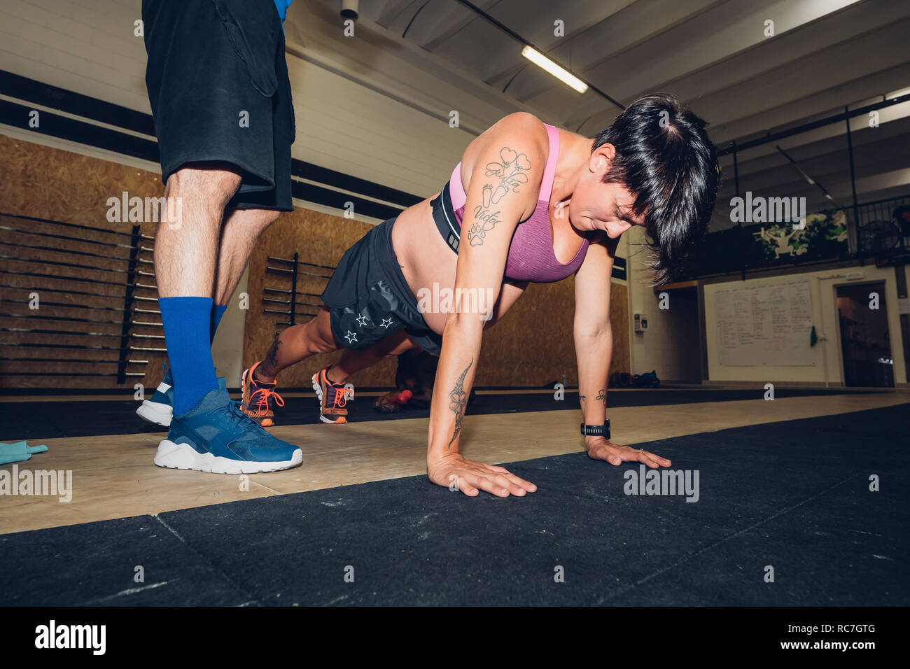 Trainer sur femme enceinte faisant pousser ups in gym Banque D'Images