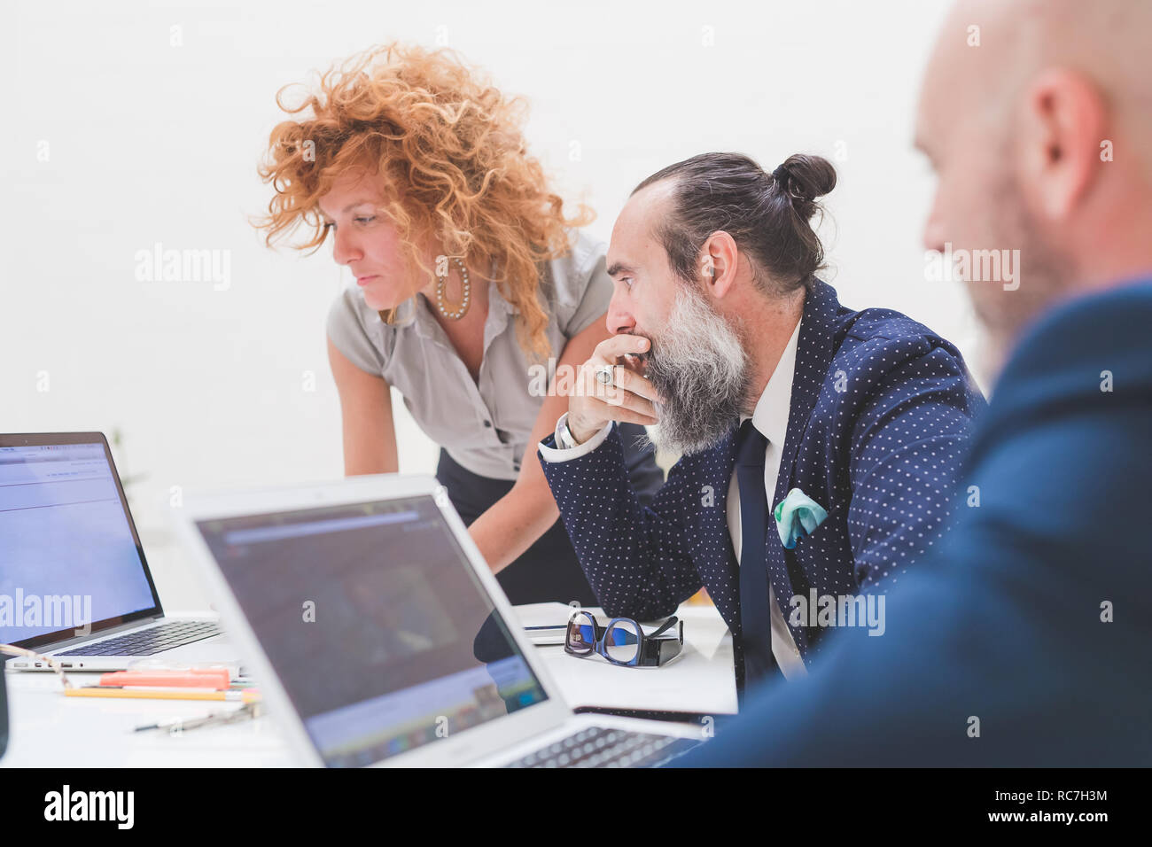 Les hommes d'affaires et à la recherche à l'ordinateur portable sur un bureau, sur épaule Banque D'Images