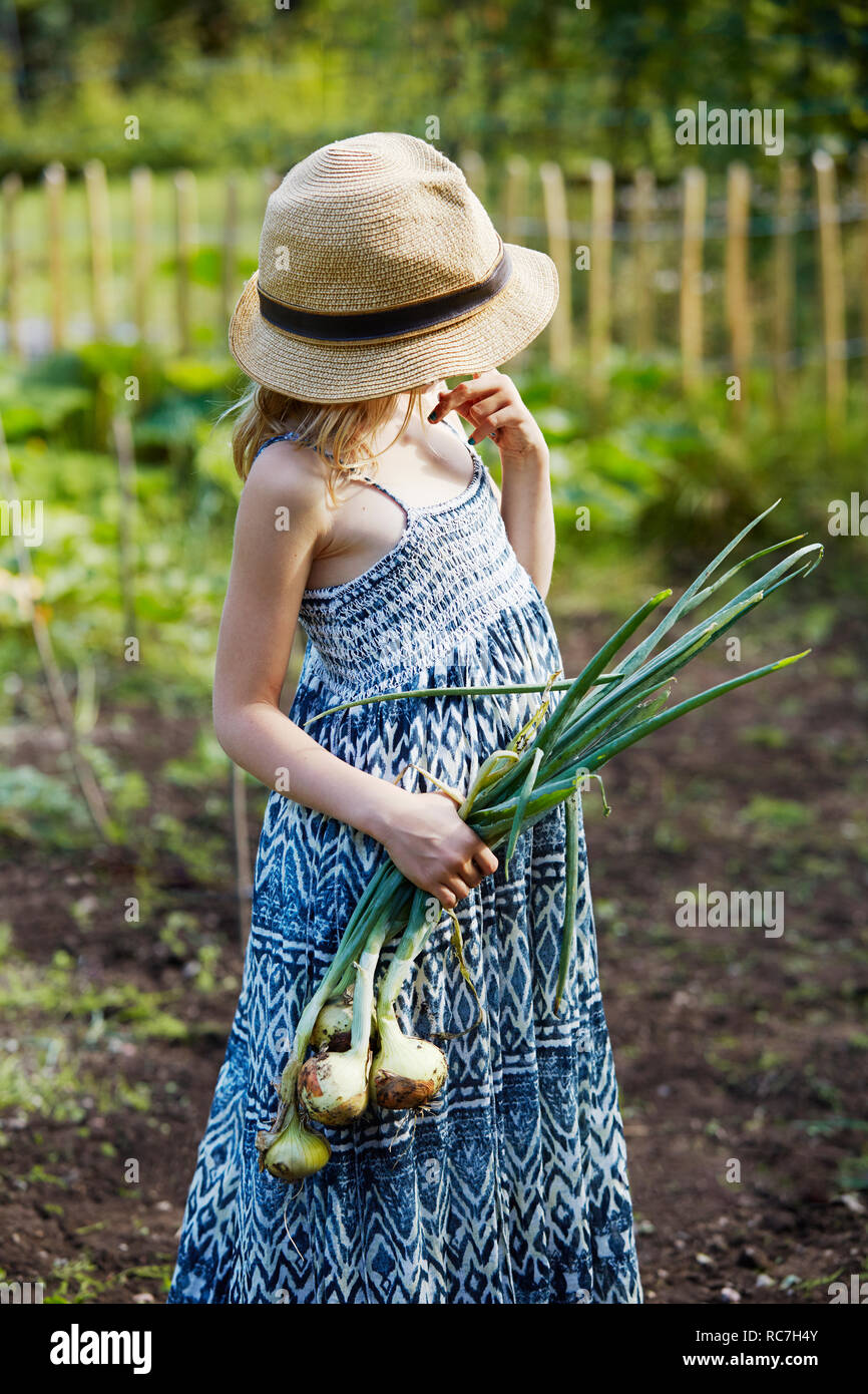 Fille avec oignons standing in field Banque D'Images