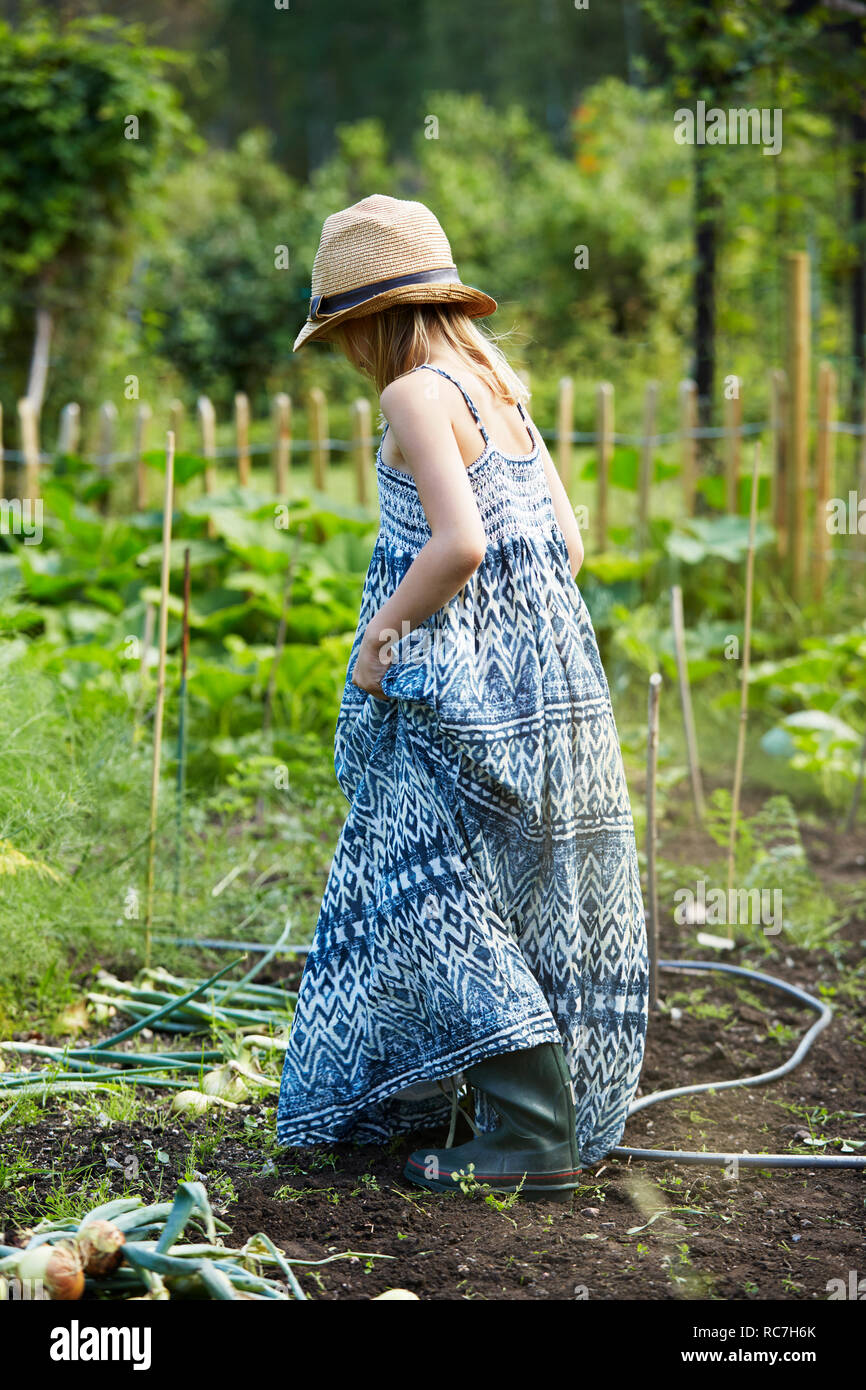 Girl in blue dress walking through field Banque D'Images