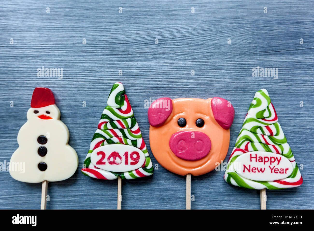 Sucettes bonbons colorés de sucreries à la nouvelle année sur un fond bleu. Arbre de Noël, bonhomme, cochon et sucettes. Sweet sucker Banque D'Images