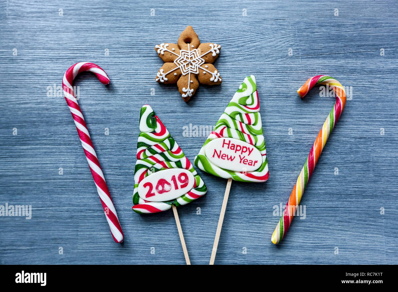 Sucettes bonbons colorés de sucreries à la nouvelle année sur un fond bleu. Arbre de Noël, bonhomme, cochon et sucettes. Sweet sucker Banque D'Images