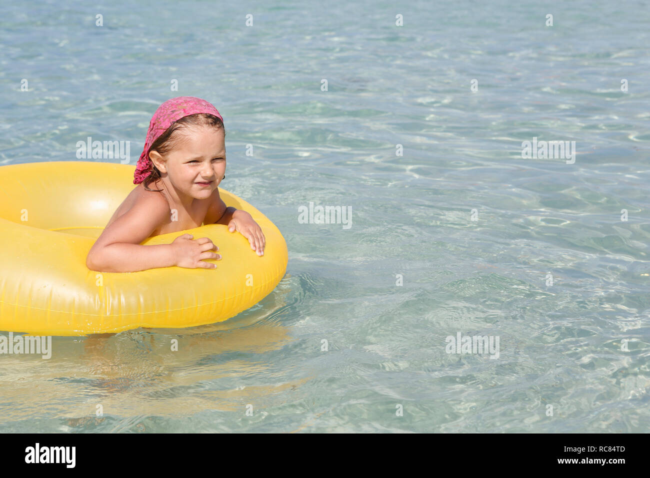 Fille jouant avec gonflable jaune en mer, San Vito, Sicile, Italie Banque D'Images