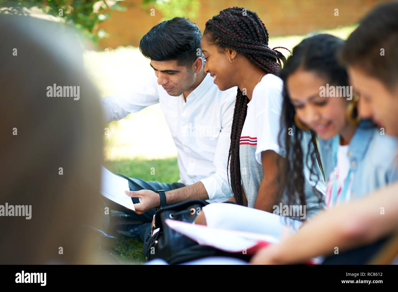 Les étudiants de l'enseignement supérieur à la paperasserie au campus du collège sur la pelouse, sur épaule Banque D'Images