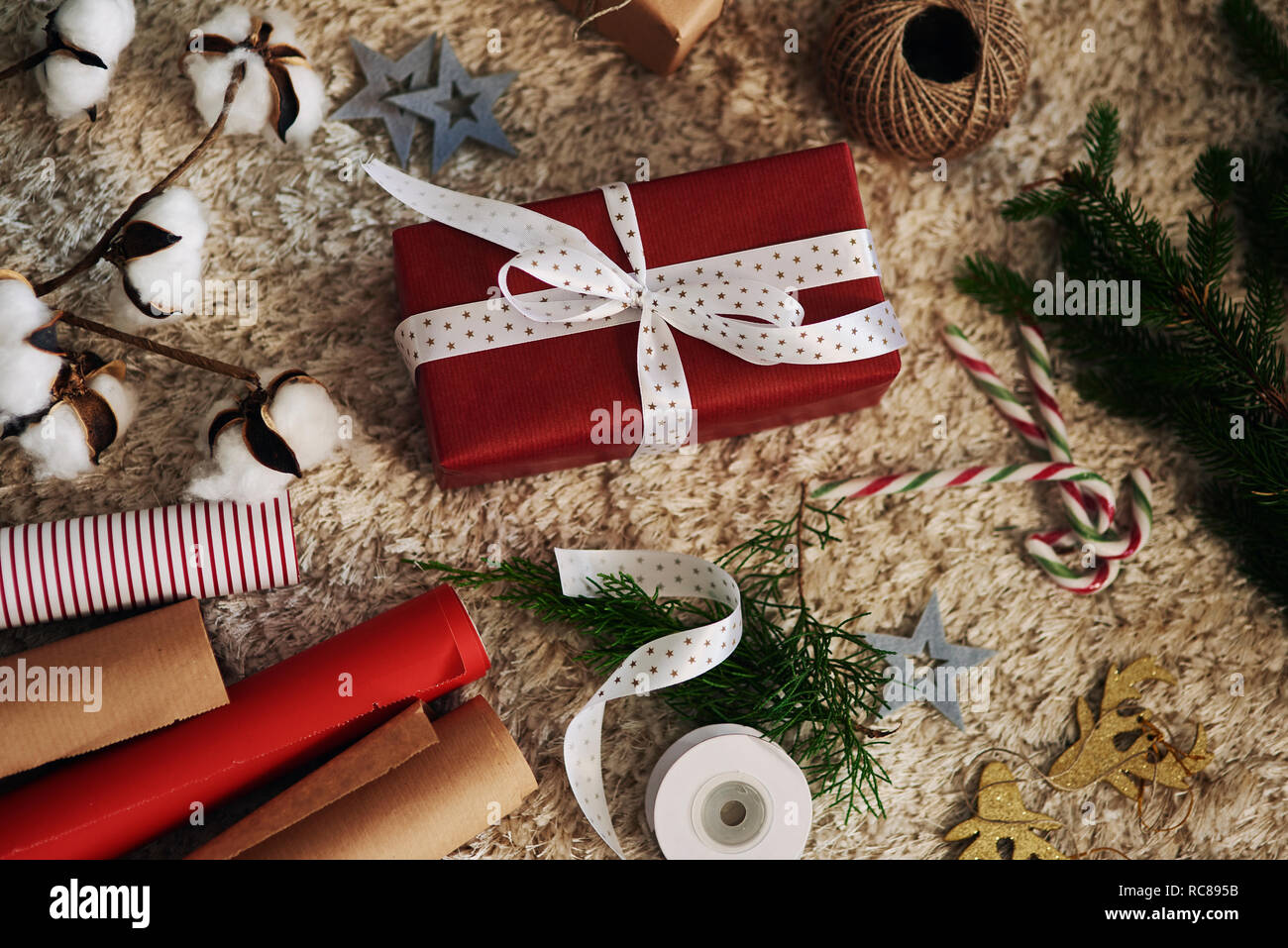 Cadeau de Noël, du papier d'emballage, de la ficelle et cloches sur tapis Banque D'Images