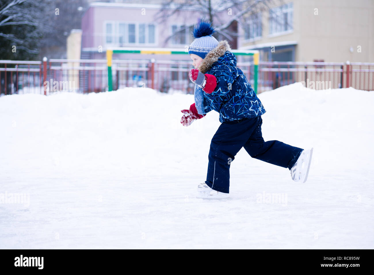 Maison de vacances actives en hiver - cute little boy patinage sur une patinoire Banque D'Images