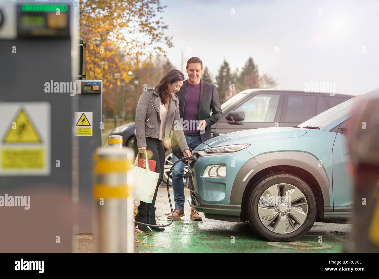 L'homme et la femme à la voiture électrique de charge charge voiture Park, Manchester, UK Banque D'Images