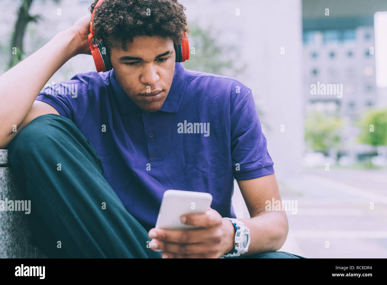 Man texting et de l'utilisation des écouteurs sur banc en béton Banque D'Images
