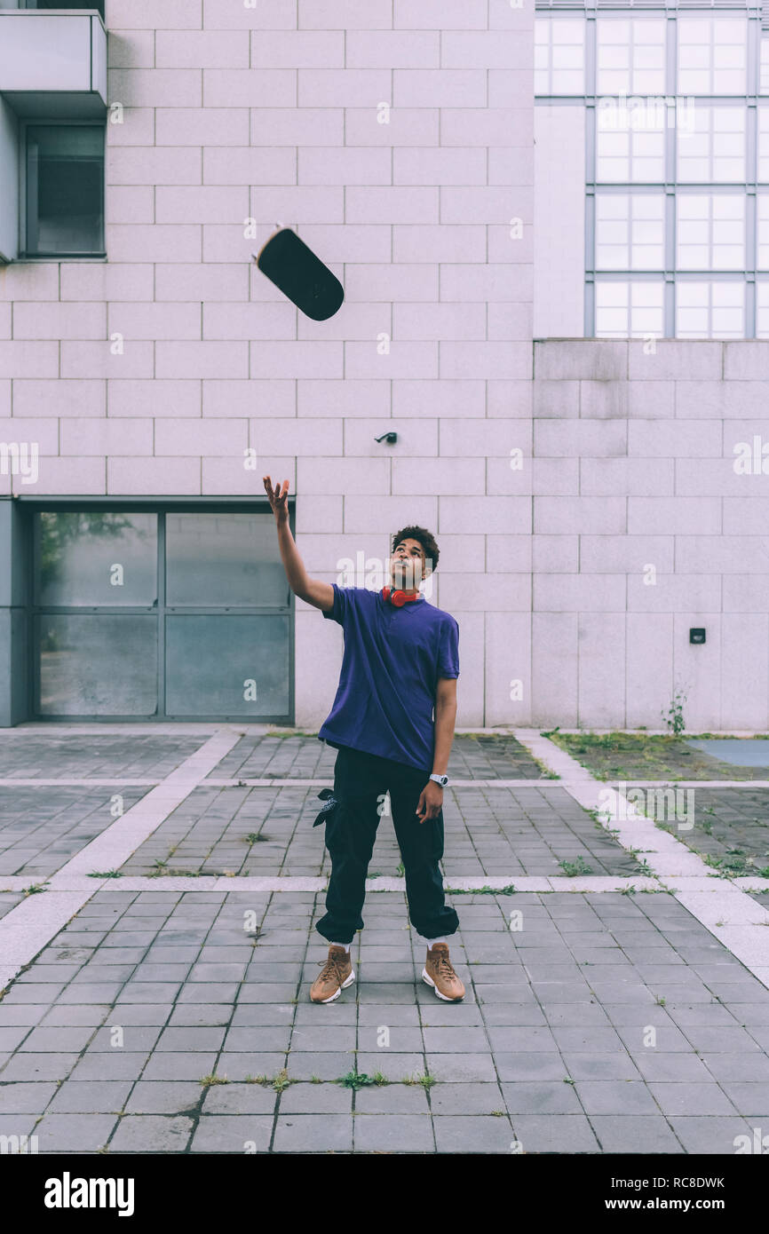 Man throwing skateboard dans l'air, Milan, Italie Banque D'Images
