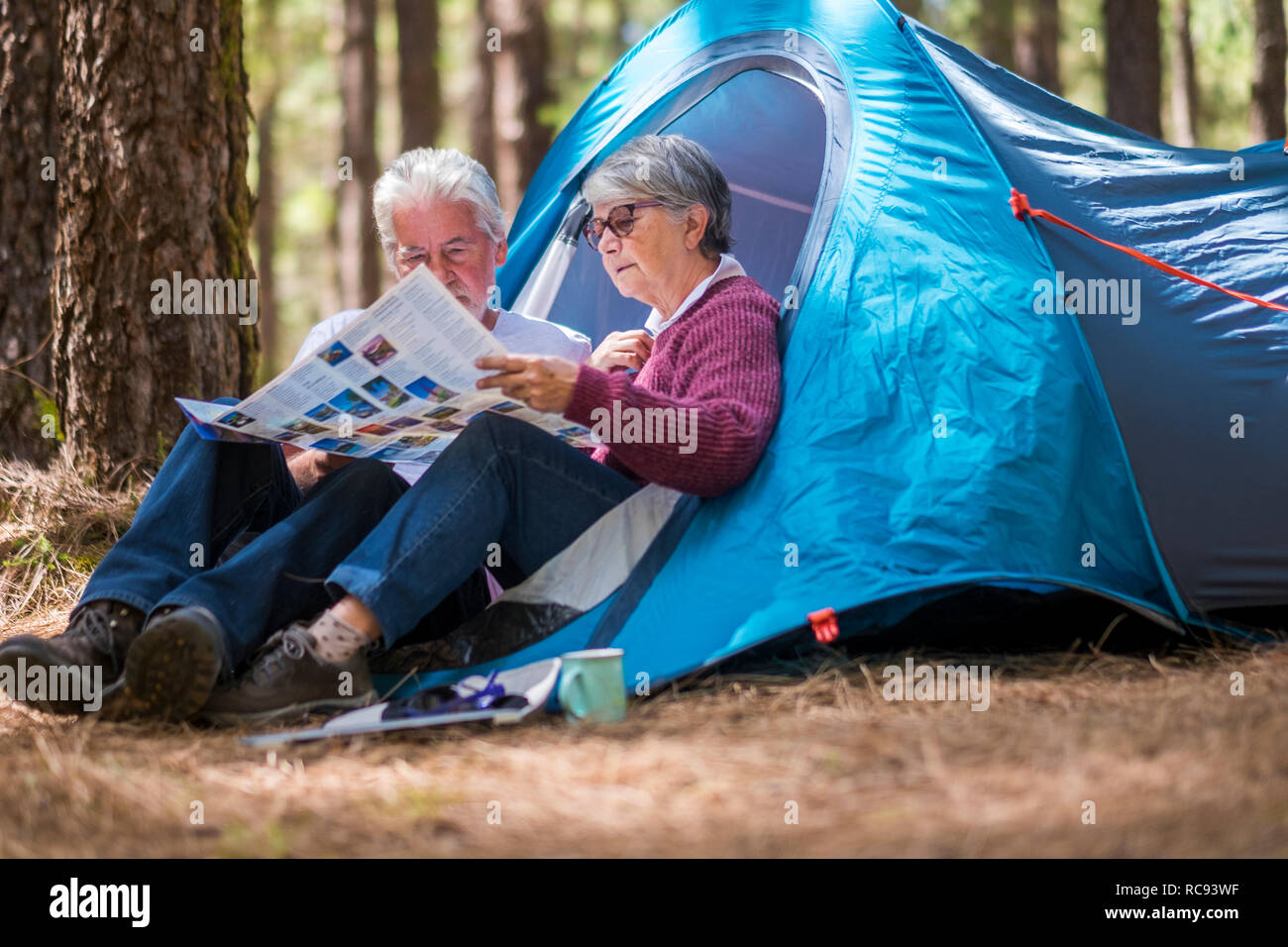 Hot mature couple retraité le enjouying outdoor camping sauvage dans la forêt à la recherche de concert une carte papier pour choisir la prochaine destination d'aventure Banque D'Images