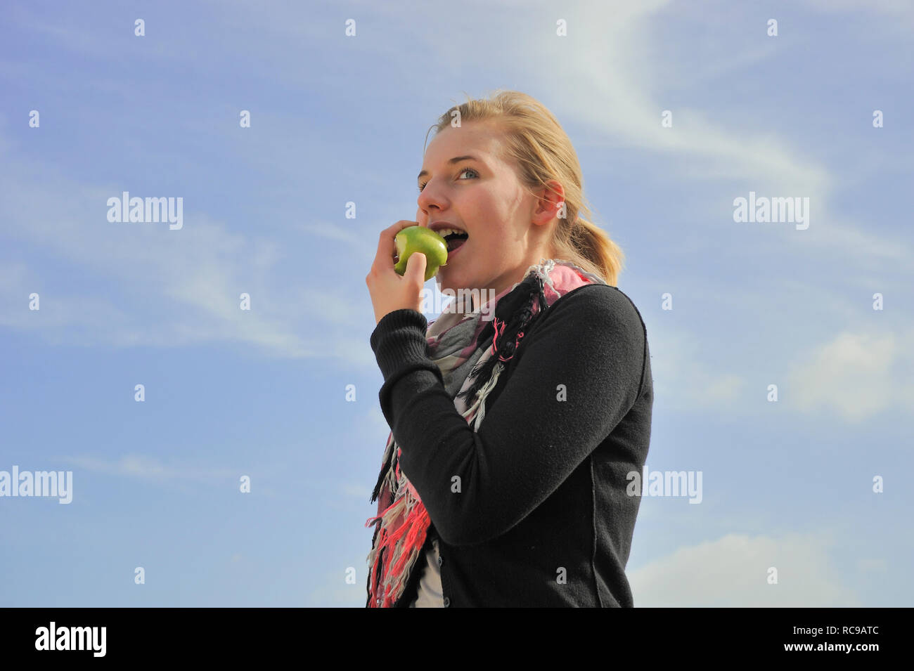 Junge Frau beisst in einen grünen Apfel - in den sauren Apfel beissen | jeune femme mange une pomme verte - d'avaler une pilule amère ou de saisir l'natt Banque D'Images