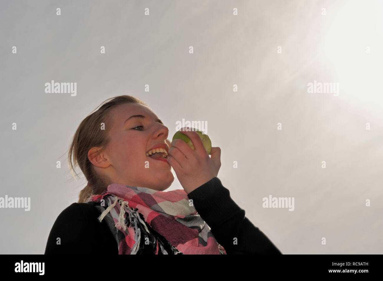 Junge Frau beisst in einen grünen Apfel - in den sauren Apfel beissen | jeune femme mange une pomme verte - d'avaler une pilule amère ou de saisir l'natt Banque D'Images