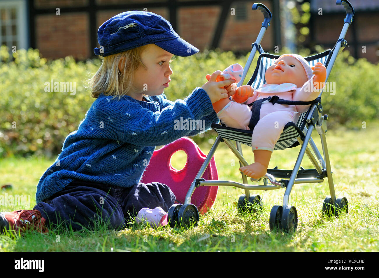 Kleines Mädchen, 2 Jahre alt, kümmert sich um ihre Puppe im Puppenbuggy | petite fille, 2 ans, prendre soin de sa poupée Banque D'Images