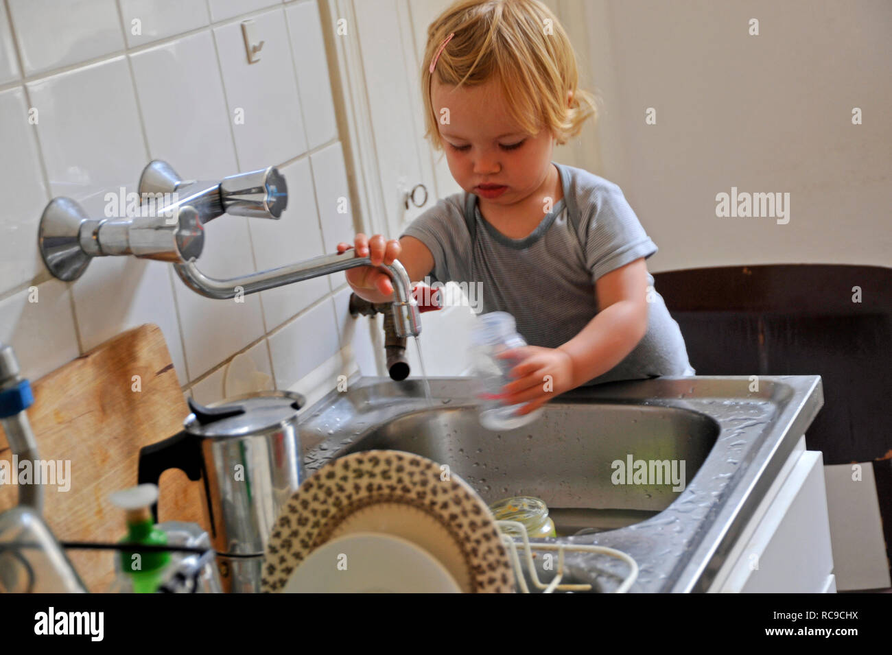 Kleinkind, Mädchen, 2 Jahre alt, in der Küche suis Wasserhahn, Abwaschbecken | petit enfant, jeune fille, âgée de deux ans, à un robinet d'eau Banque D'Images
