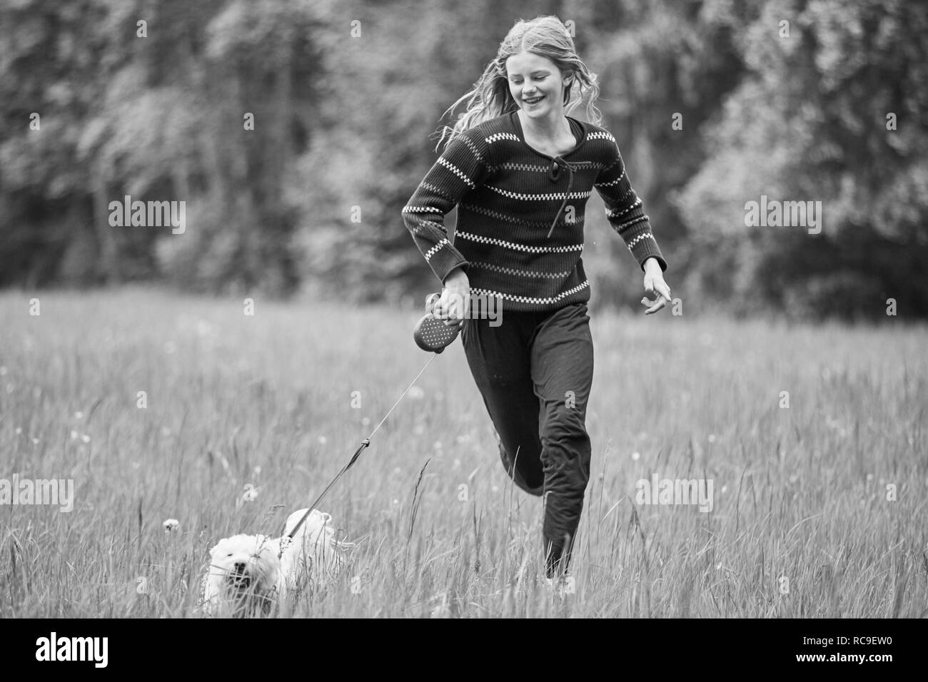 Girl running with dog in field Banque D'Images