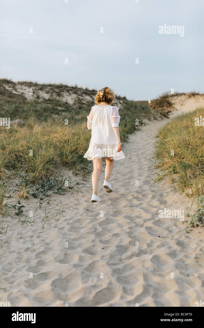 Jeune femme en robe blanche marche sur les dunes côtières, vue arrière, Menemsha, Martha's Vineyard, Massachusetts, USA Banque D'Images