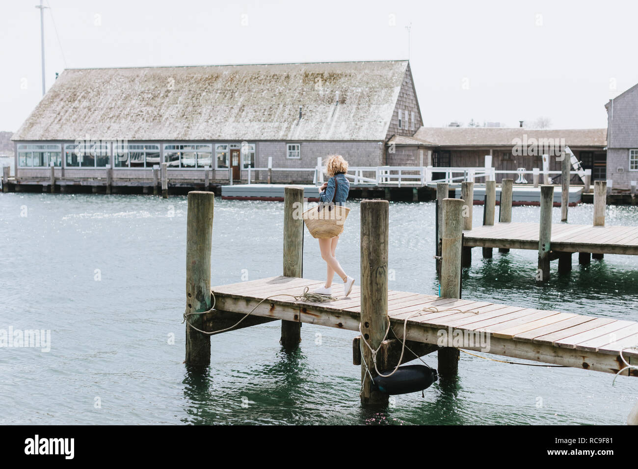 Jeune femme se promenant sur la jetée en bois, Menemsha, Martha's Vineyard, Massachusetts, USA Banque D'Images
