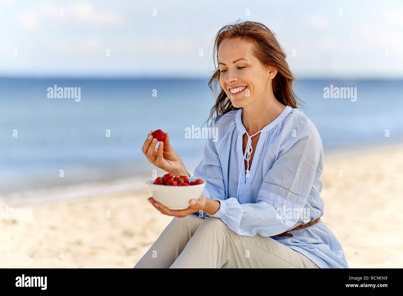 Happy woman eating strawberries on été plage Banque D'Images