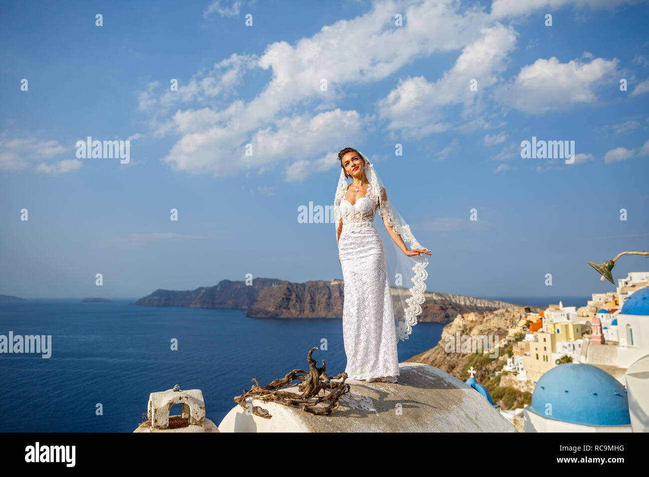 Mariée en robe blanche sur le toit élevé de Santorin, sur la mer Banque D'Images