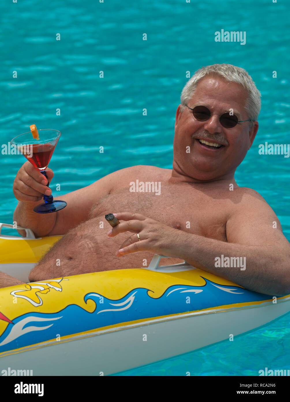 Älterer Mann genießt das Leben im kleinen im Schlauchboot Piscine d'| homme âgé avec un canot en caoutchouc dans la piscine Banque D'Images