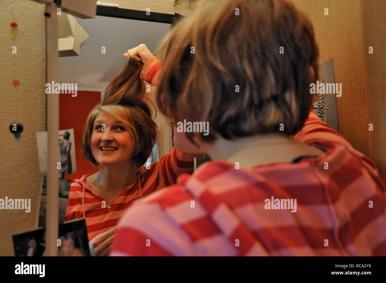 Junge Frau zieht Grimassen vor dem Spiegel in Ihrem Zimmer | young woman making funny grimaces devant un miroir dans sa chambre Banque D'Images