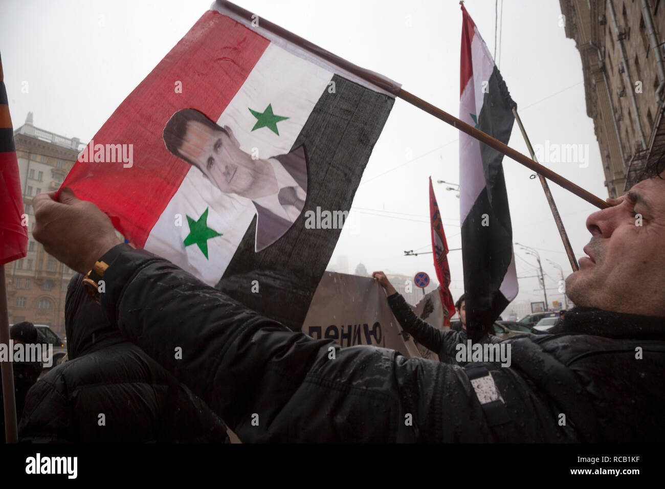 Réfugiés syriens tenant un drapeau syrien avec un portrait du président Bachar al-Assad, en face de l'ambassade des Etats-Unis dans le centre de Moscou, Russie Banque D'Images