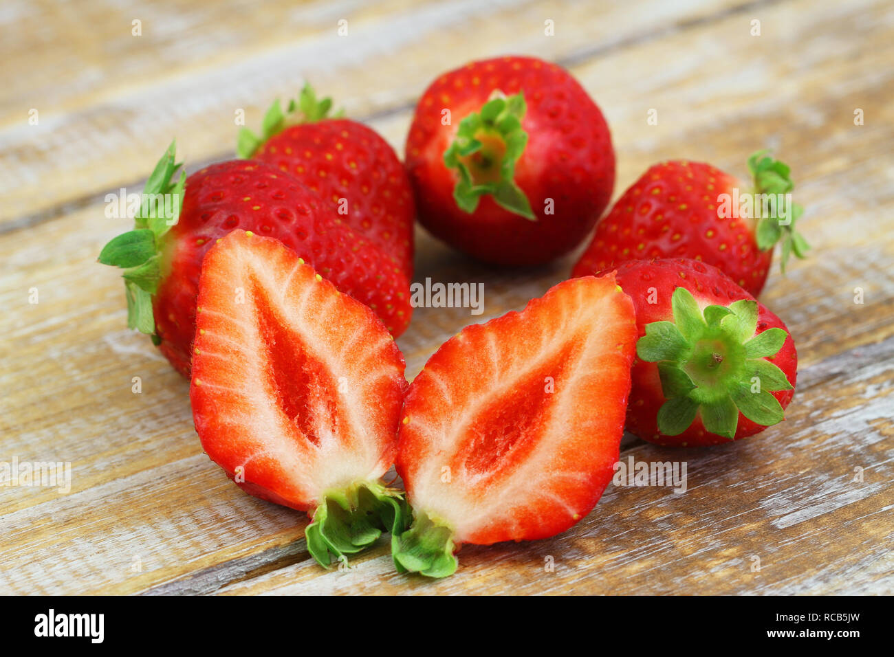 Fraises fraîches coupées en deux sur la surface en bois rustique, gros plan Banque D'Images