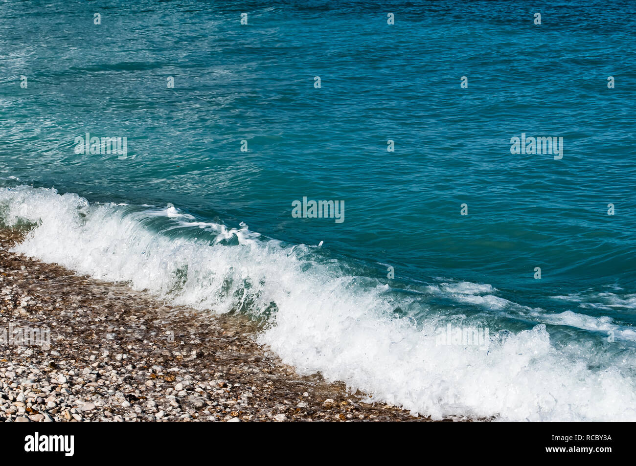 Matériel roulant dans les vagues sur la plage grecque Banque D'Images