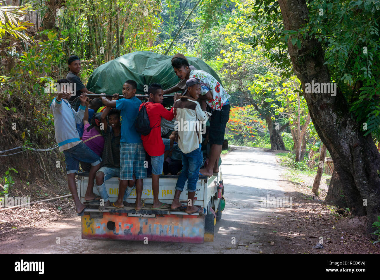 Les jeunes hommes un tour de l'attelage à l'arrière de transports locaux surpeuplés déjà près de Dili. Banque D'Images