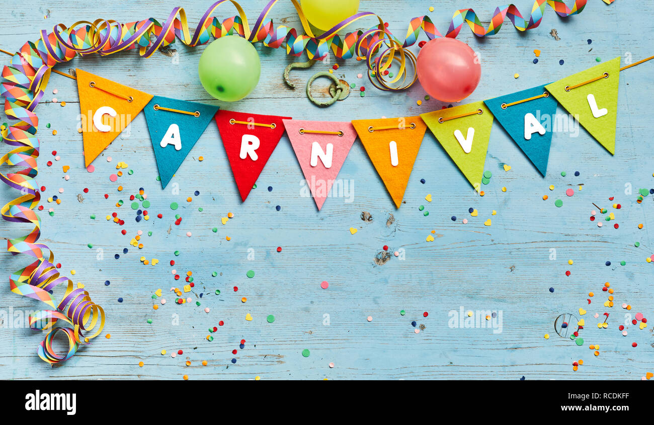 Arrière-plan de carnaval avec festive bunting, ballons et banderoles formant une bordure autour de l'espace de copie sur bois bleu avec des confettis Banque D'Images