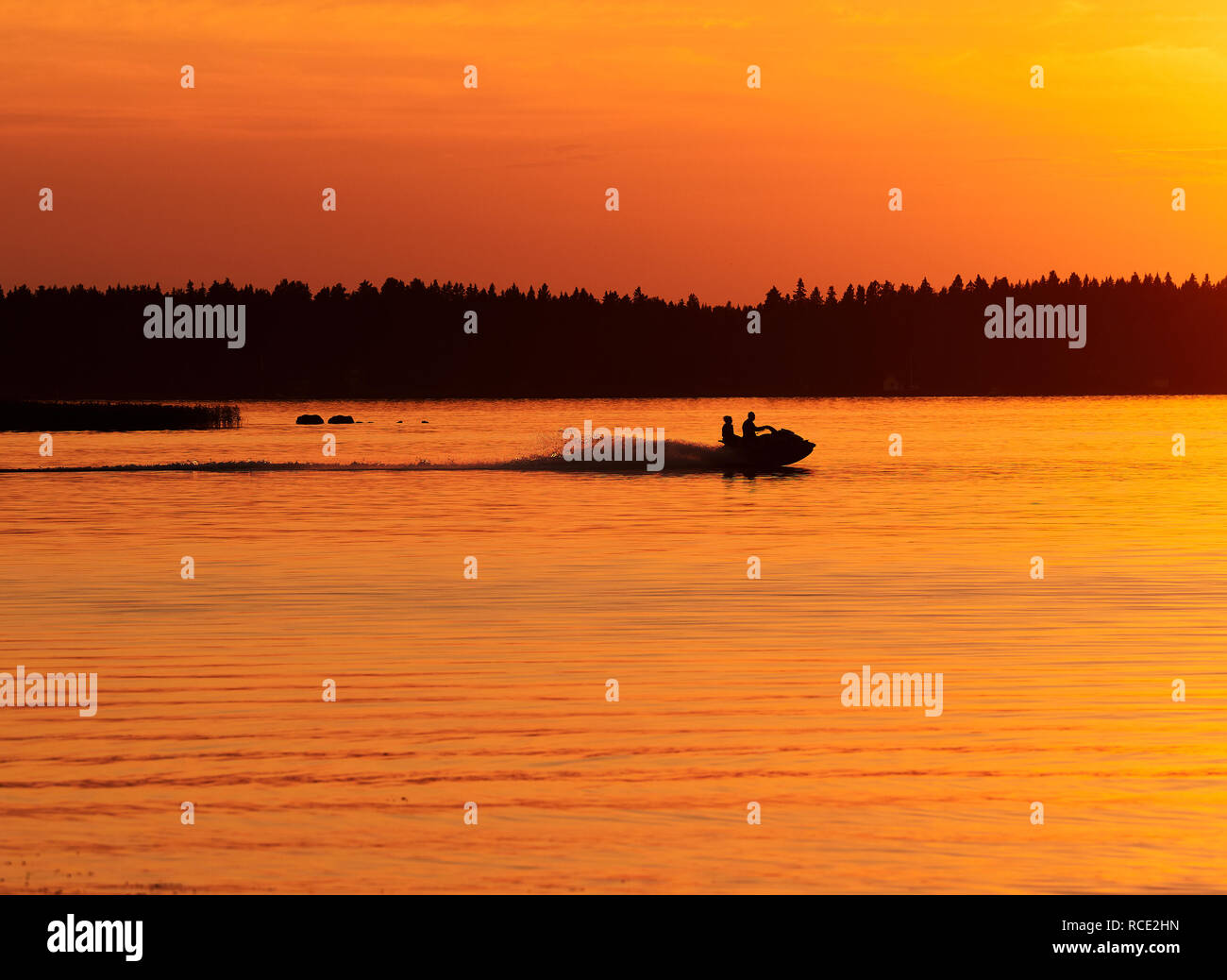 Conduire un jet-ski dans le calme de l'eau de mer en Vaasa, Finlande. Ciel de coucher du soleil et des vagues colorées dans l'eau. L'activité, passe-temps et loisirs consept. Banque D'Images