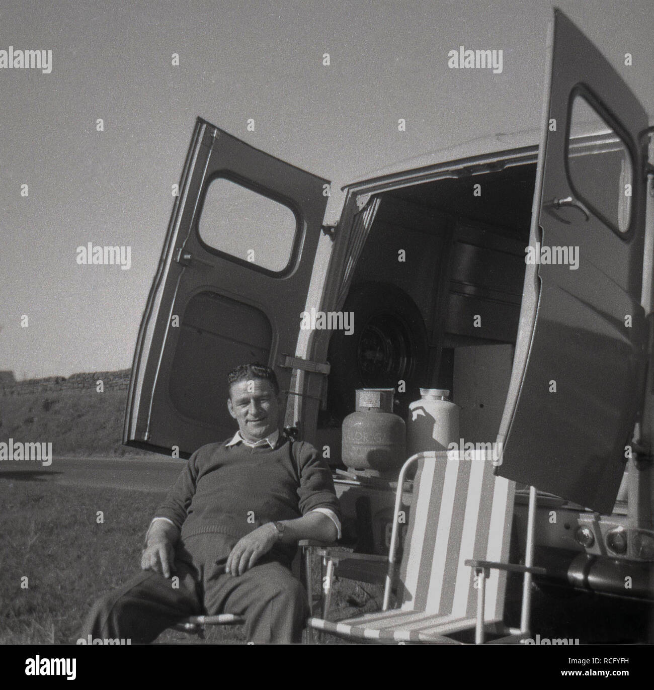 1960s, historique, Oh les plaisirs simples de la vie... un homme se détend dans une chaise pliante à l'arrière de son camion Morris commercial J4 garé dans un champ avec ses portes arrière largement ouvertes, Angleterre, Royaume-Uni Banque D'Images