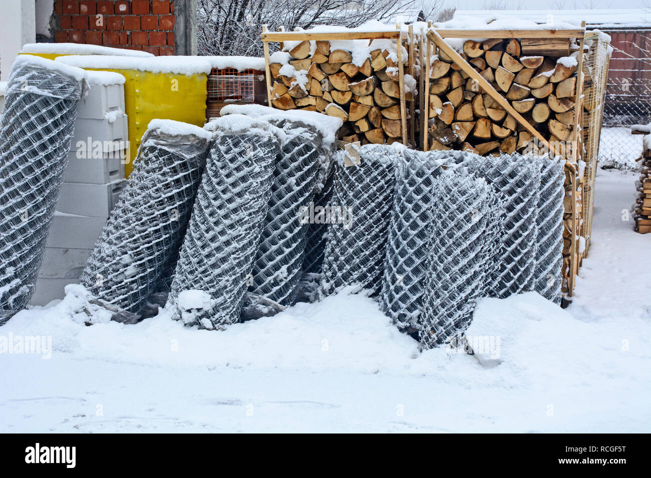 Bois de chauffage, matériaux de construction et des grillages dans des conditions hivernales sur l'ouverture et de l'entrepôt couvert de neige. Banque D'Images